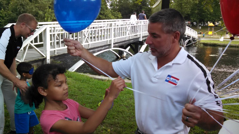 David Mueller is spinning the next Cuff the Burglar contestant in line while Dave Davis hands out balloons.